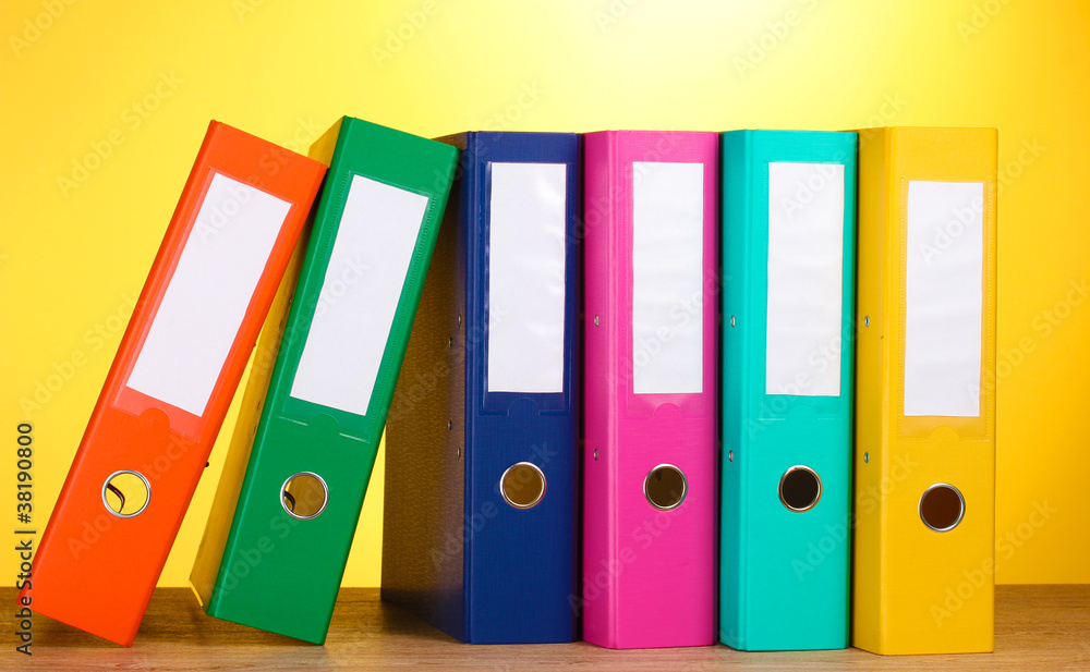 bright office folders on wooden table on yellow background bright office folders on wooden table on yellow background