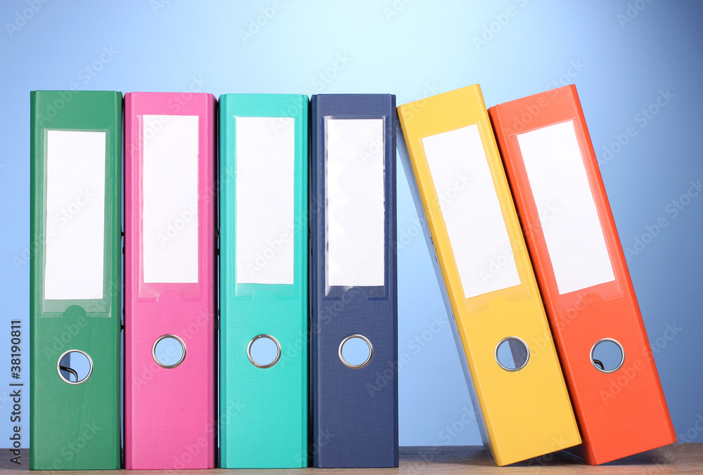 bright office folders on wooden table on blue background bright office folders on wooden table on blue background