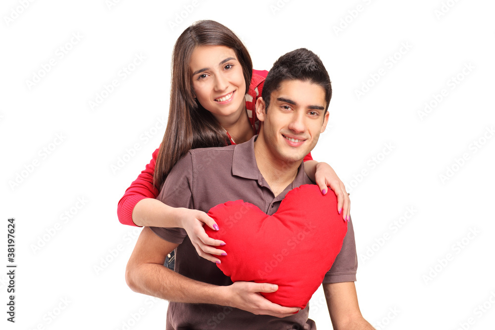 Young loving couple in an embrace holding a red pillow