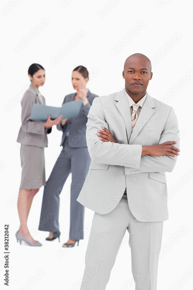 Confident tradesman with colleagues behind him Confident tradesman with colleagues behind him