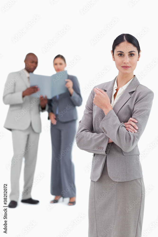 Serious saleswoman with colleagues behind her Serious saleswoman with colleagues behind her