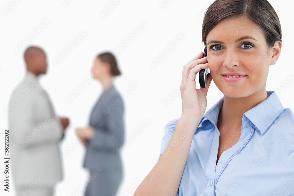 Tradeswoman with mobile phone and associates behind her Tradeswoman with mobile phone and associates behind her