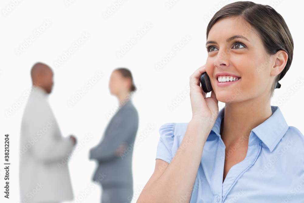 Smiling businesswoman with mobile phone and associates behind he Smiling businesswoman with mobile phone and associates behind he