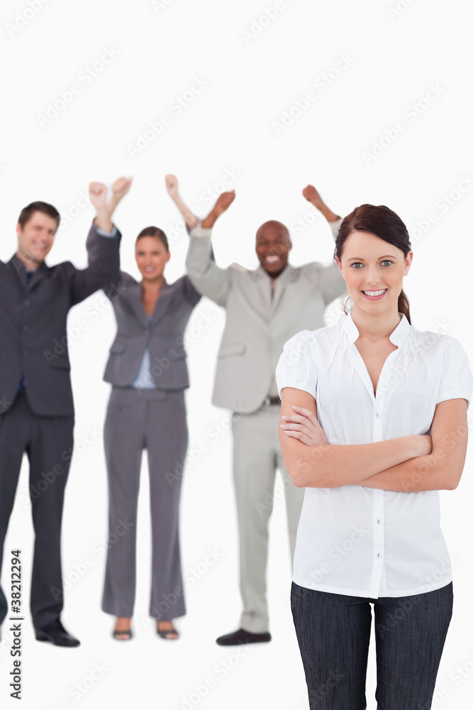 Smiling businesswoman with cheering co-workers behind her Smiling businesswoman with cheering co-workers behind her