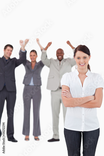 Smiling businesswoman with cheering co-workers behind her