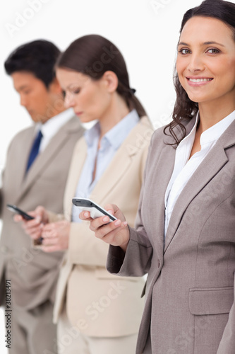 Smiling businesswoman with cellphone next to colleagues