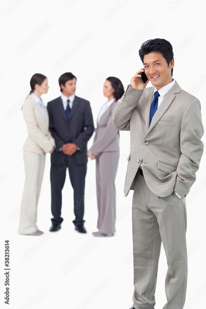 Businessman on cellphone with colleagues behind him