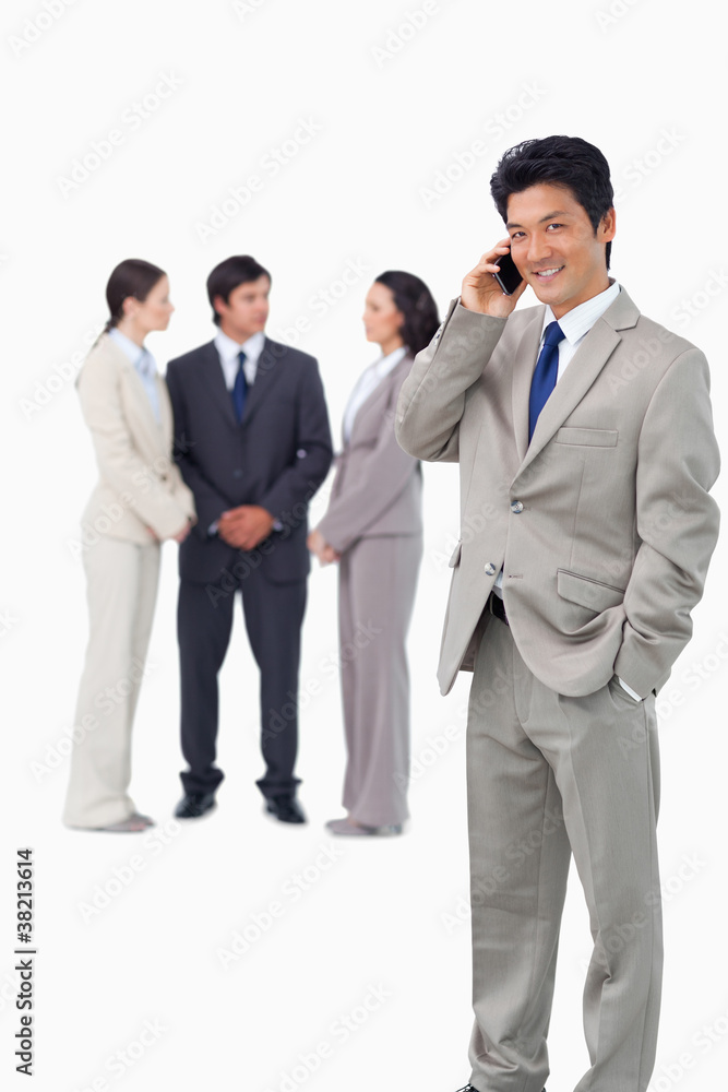 Businessman on cellphone with colleagues behind him Businessman on cellphone with colleagues behind him