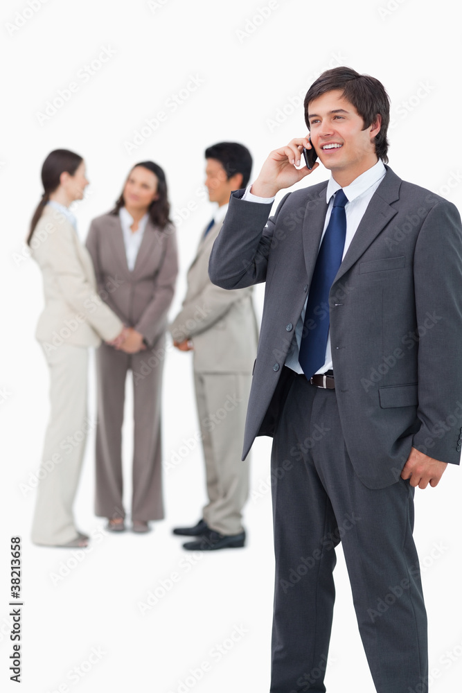 Smiling tradesman on cellphone with team behind him Smiling tradesman on cellphone with team behind him