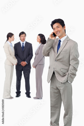 Businessman with cellphone and colleagues behind him