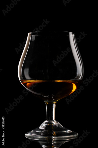 Glass of cognac on black background © Africa Studio