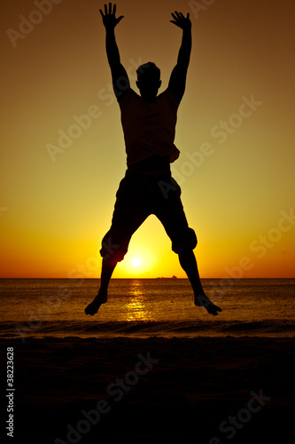 Fototapeta Naklejka Na Ścianę i Meble -  Silhouette of a man jumping on the beach at sunset