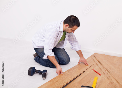 Casual man or worker installing flooring