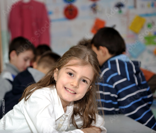 Happy little girl in school with her friends arround