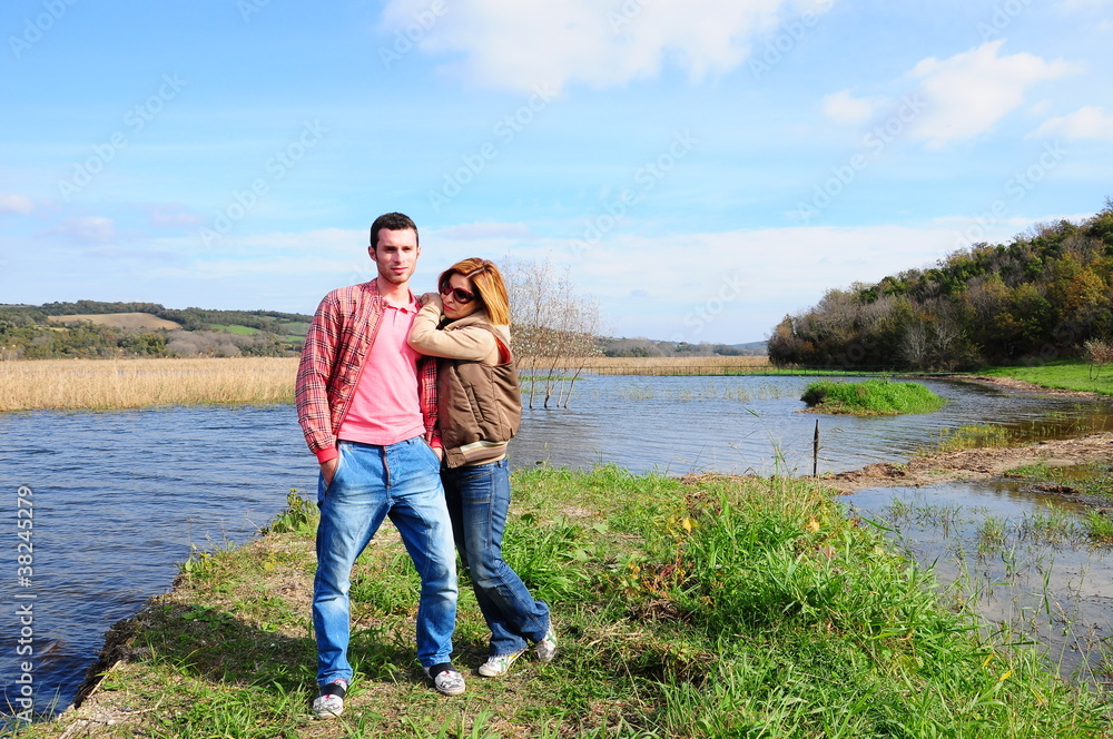 happy young couple together by river on grass