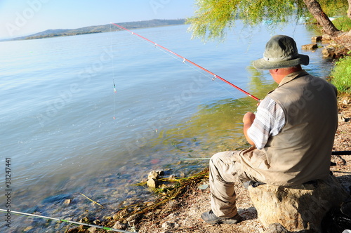 fisherman is angling, sitting by lake
