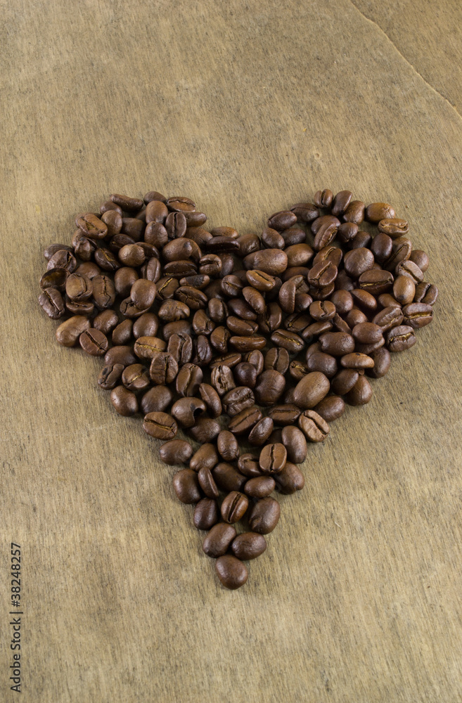 Coffee beans in a heart shape on a wooden table background Coffee beans in a heart shape on a wooden table background