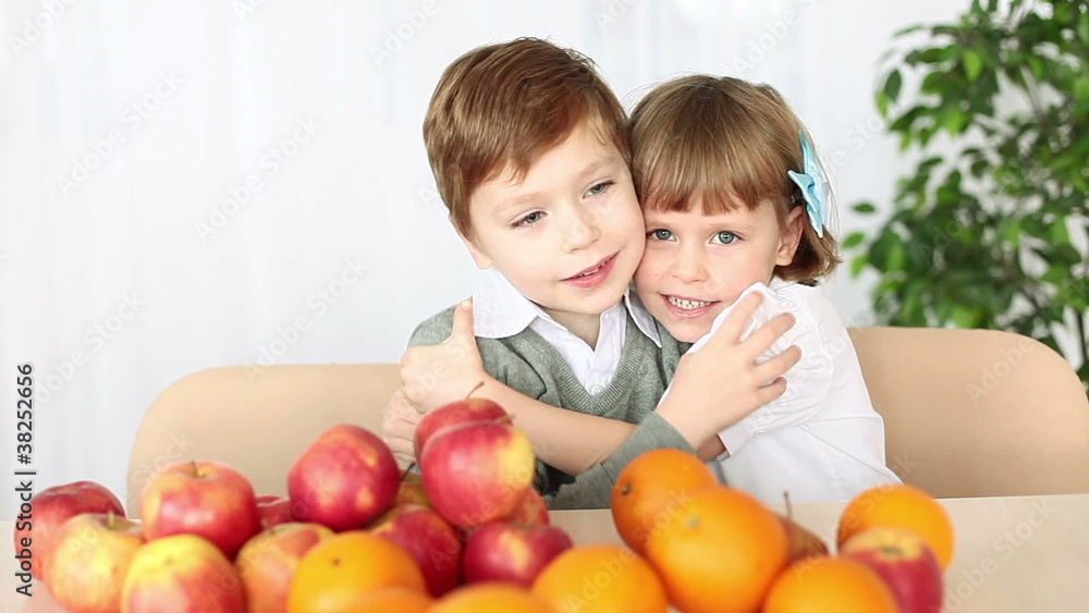 Brother and sister hugging. They sit at the table. Brother and sister hugging. They sit at the table.
