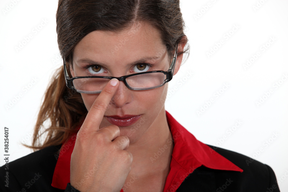 A businesswoman repositioning her glasses. A businesswoman repositioning her glasses.