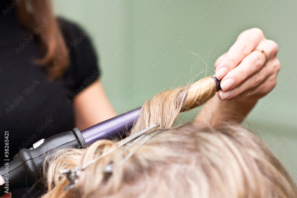 Naklejka premium Hairdresser to curl the hair in a beauty salon