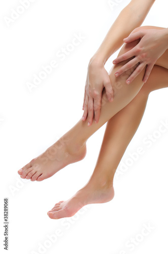 Close up of slender naked legs being massaged isolated on white