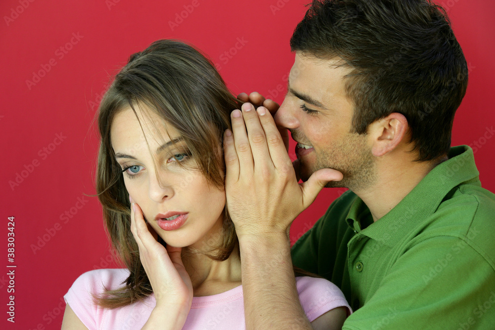 Man whispering a secret to a young woman Man whispering a secret to a young woman