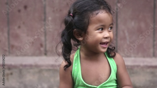 Happy little Asian girl smiling at camera and playing