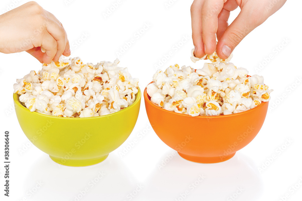 Hands of children eating popcorn on a white background Hands of children eating popcorn on a white background