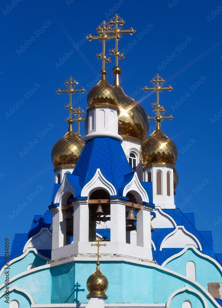 Cupolas of Russian orthodox church against blue sky.