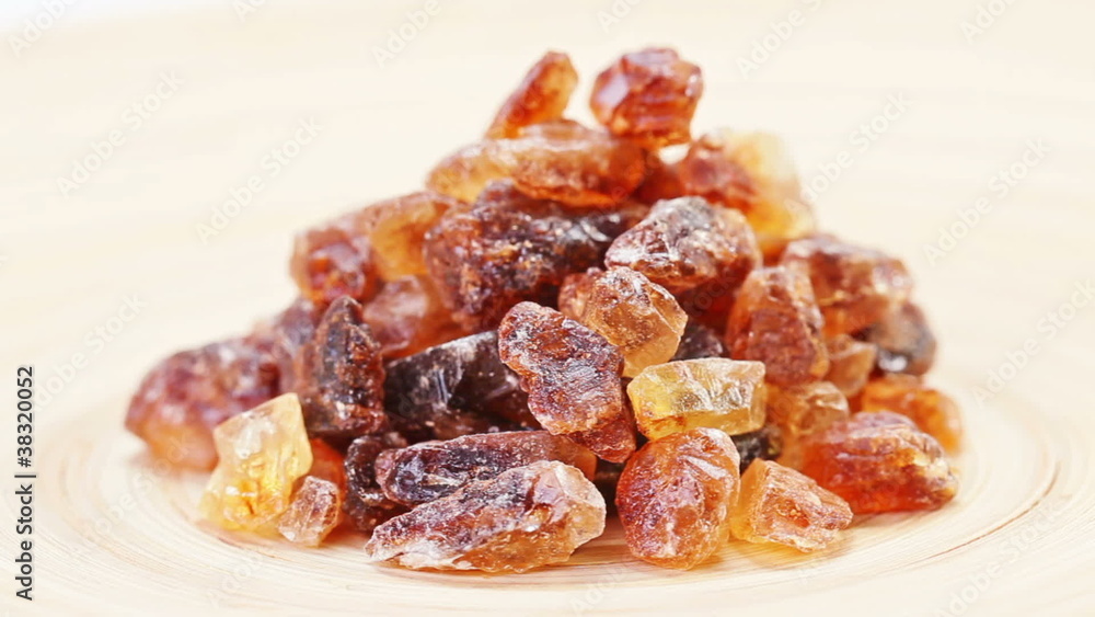 Brown lump cane sugar heap rotating on a wooden plate Brown lump cane sugar heap rotating on a wooden plate