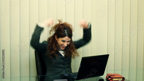 Jubilating female clerk with laptop sitting in office photo