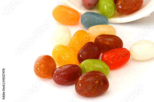 Colourful candies in a brown bowl on white background