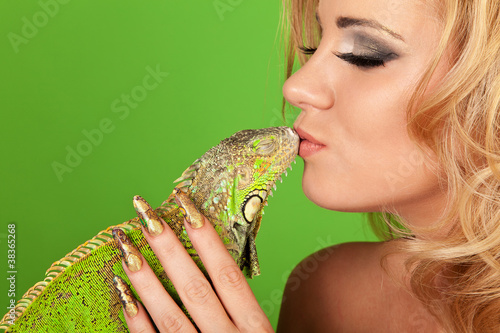 Portrait of a young woman with beautiful manicure kissing a igua photo