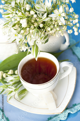 tea in a cup of white flowers and lilies of the valley