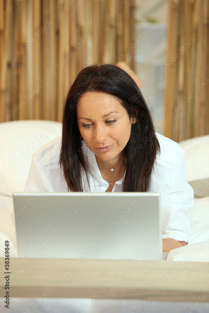 Brunette laid in bed with laptop Brunette laid in bed with laptop