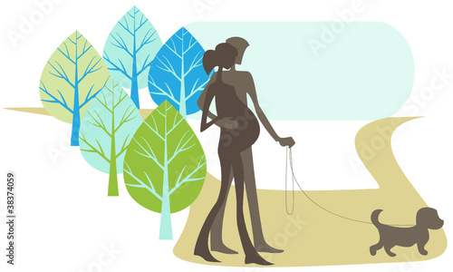 The man and pregnant woman walk in the park with their dog.