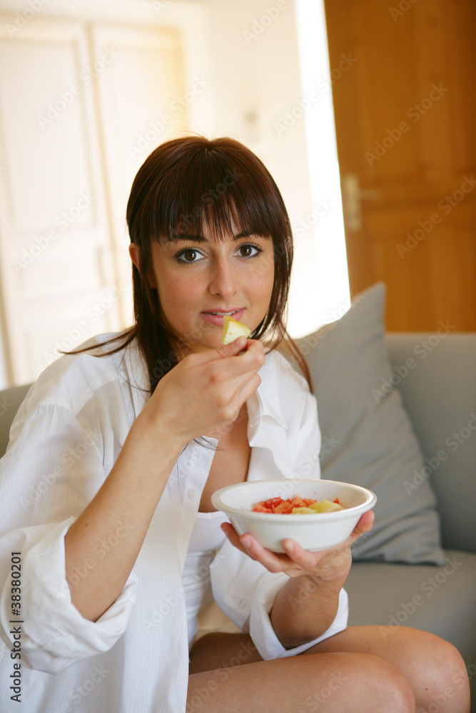 Portrait of a young woman eating a salad of fruits Portrait of a young woman eating a salad of fruits