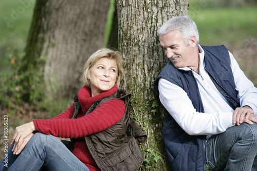Middle-aged couple sat by tree © auremar
