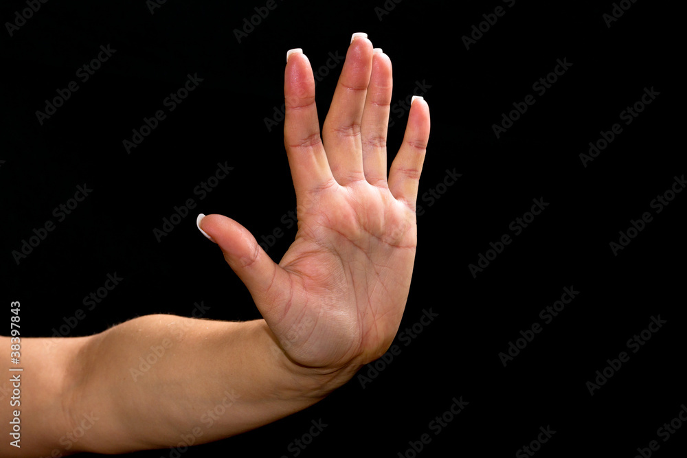 Female hand showing stop symbol over black background Female hand showing stop symbol over black background