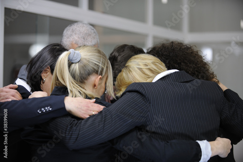 Team building event: businessmen in 'group hug' in office photo