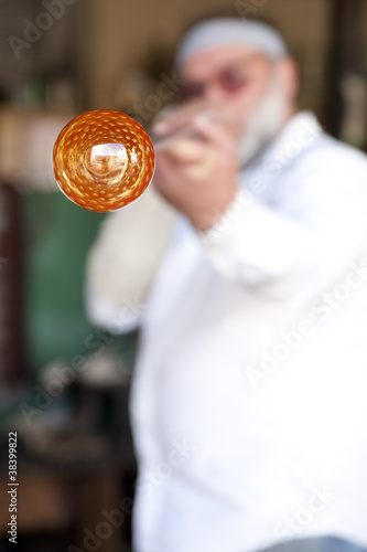 Glass blower shaping molten glass into a drinking goblet