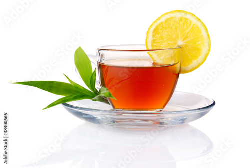 Cup of black tea with lemon and green leaves isolated