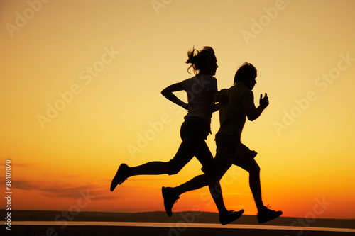 Obraz na płótnie Young couple run together on a sunset w salonie