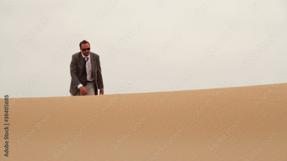 Businessman walking on dune in desert Businessman walking on dune in desert