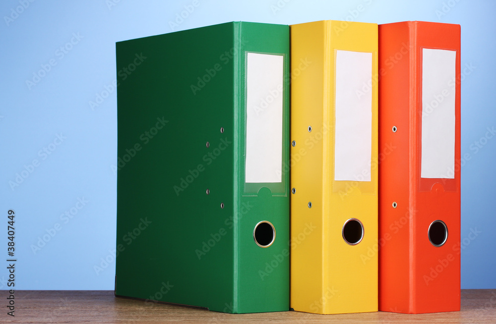 bright office folders on wooden table on blue background