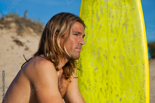 Long haired blonde surfer and surfboard.