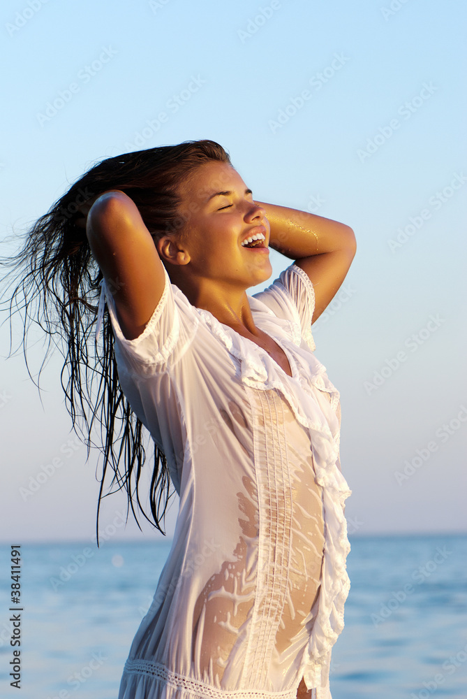 Beautiful girl in a white wet transparent dress costs in sea Stock Photo