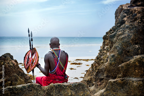 Maasai sitting by the ocean on the beach photo