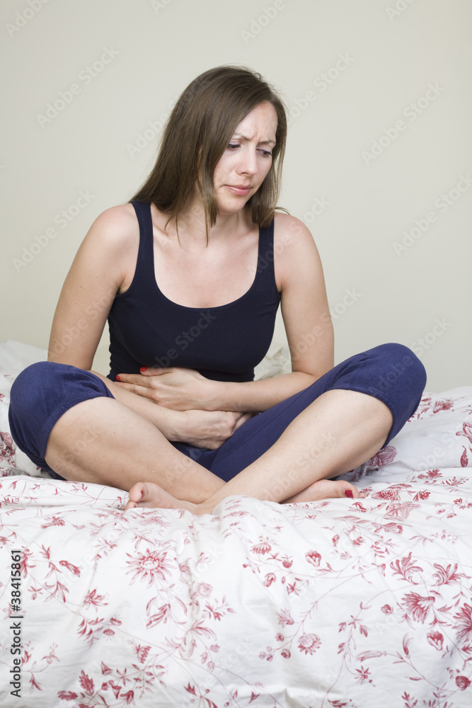 Schöne Frau mit Bauchschmerzen im Bett sitzend Schöne Frau mit Bauchschmerzen im Bett sitzend