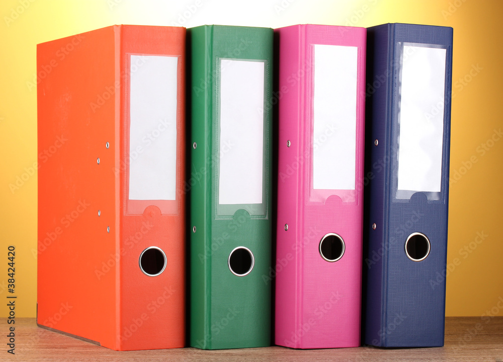 bright office folders on wooden table on yellow background. bright office folders on wooden table on yellow background.